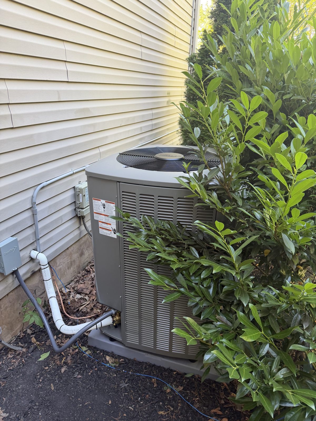 Heat pump condenser installed beside a landscaped Philadelphia-area home