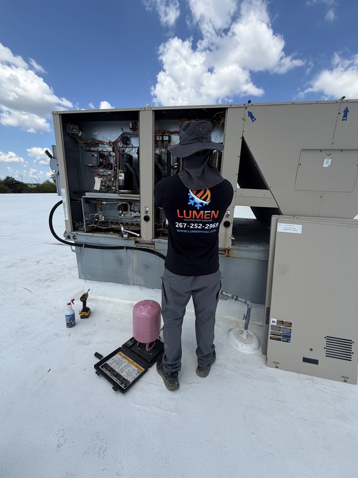 Lumen Heating and Cooling technician servicing a commercial rooftop HVAC unit