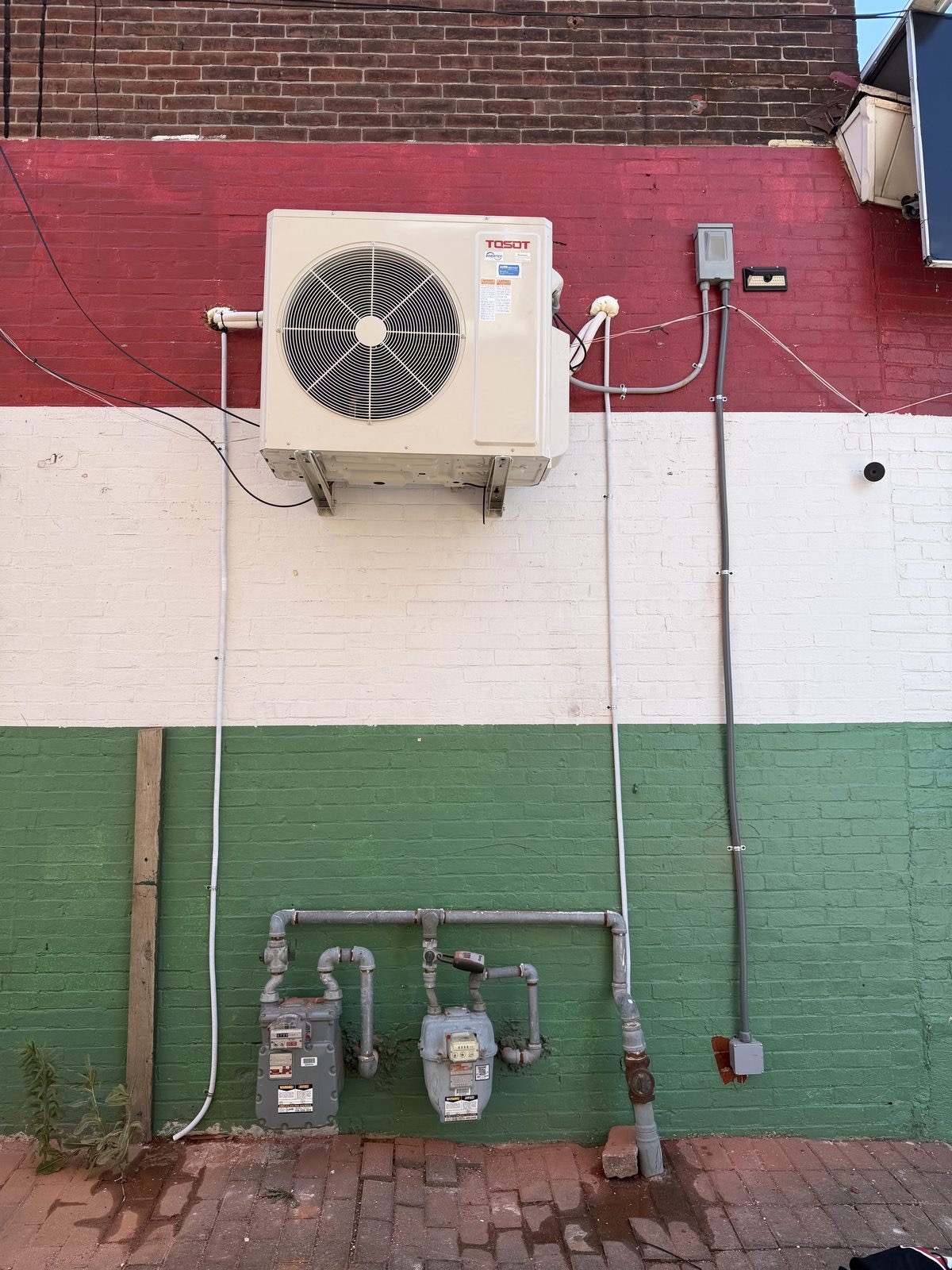 Ductless mini-split outdoor unit mounted on a painted Philadelphia rowhome wall by Lumen Heating and Cooling