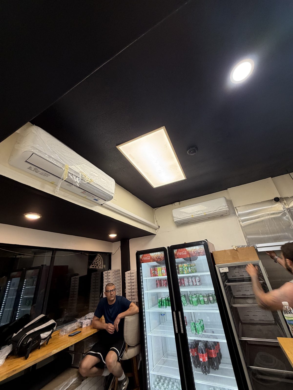 Ductless mini-split wall unit installed in a retail store above the beverage coolers by Lumen Heating and Cooling