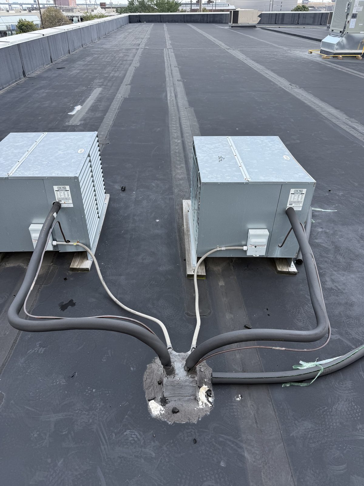 Two ductless mini-split outdoor units on a flat rowhome roof with insulated line sets run by Lumen Heating and Cooling