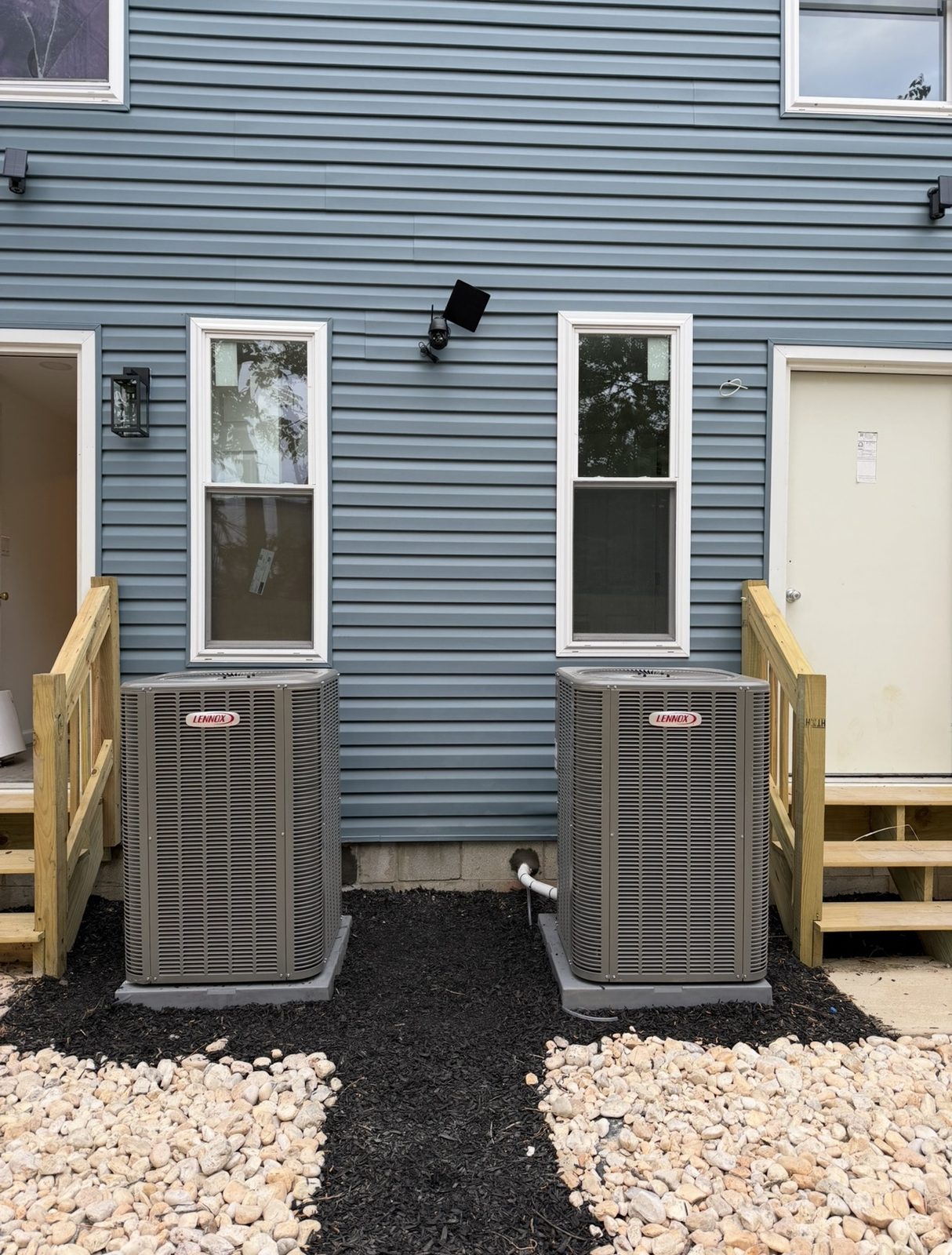 Two Lennox condensers installed side by side behind adjoining townhomes by Lumen Heating and Cooling